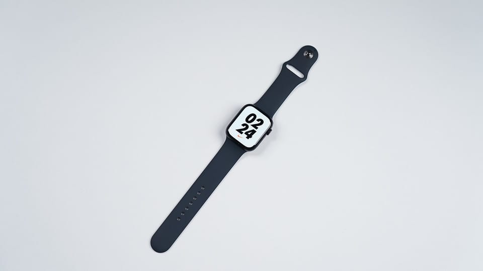 An Apple Watch with a dark band lying on a white surface