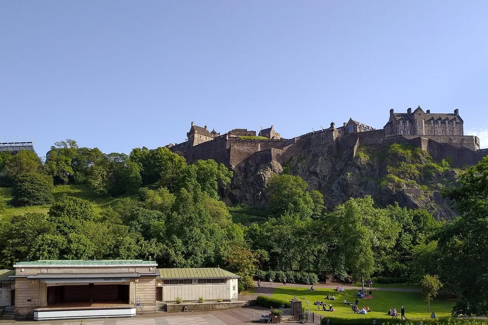 Edinburgh Castle on its rock above the trees of Princes Street Gardens on a clear day