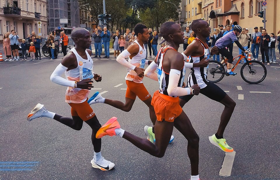 Four elite runners in a leading group on a Berlin street during the 2023 Berlin Marathon