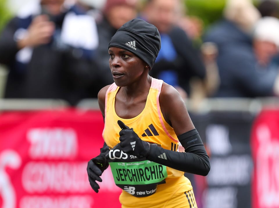 Peres Jepchirchir in a yellow vest and black hat running past spectators at the London Marathon