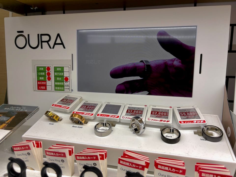 A shop display of Oura smart rings with a screen showing a hand wearing a ring