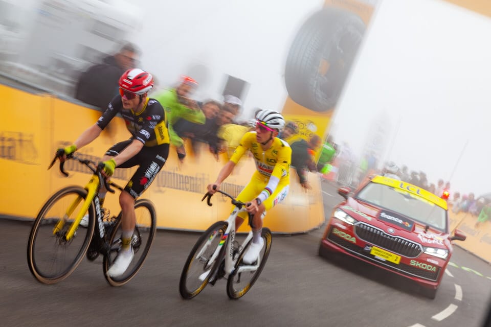 Jonas Vingegaard and Tadej Pogačar riding side by side on a mountain stage of the 2025 Tour de France