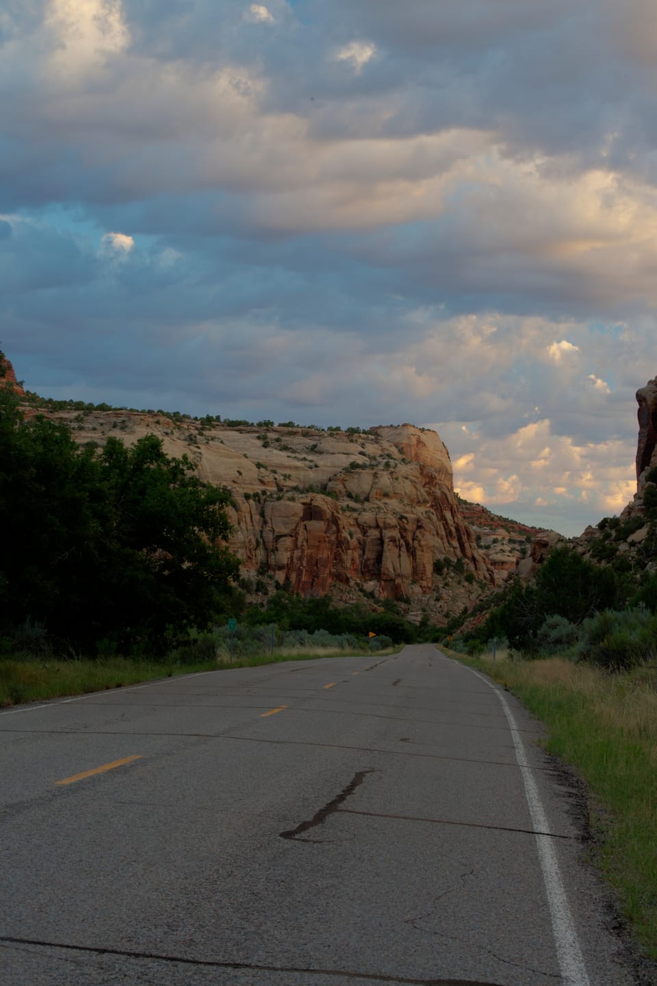 A road running between sandstone cliffs under heavy clouds